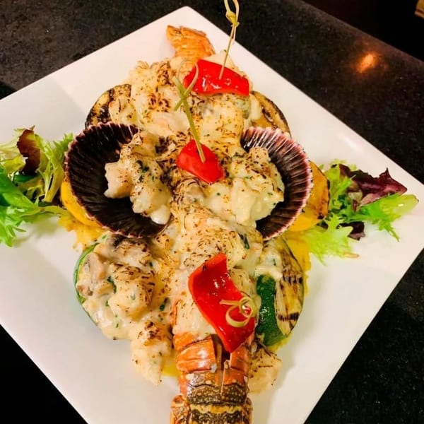 Peruvian lobster and scallops in a creamy sauce, garnished with red peppers and greens.